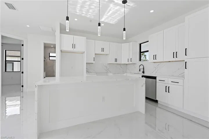 Kitchen with white cabinets, stainless steel dishwasher, and recessed lighting