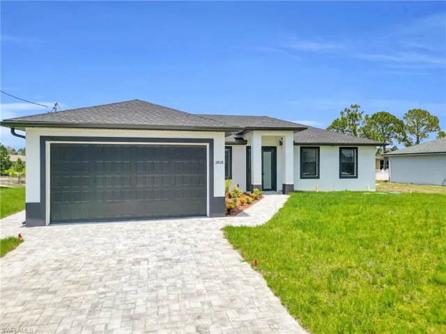 Prairie-style home with an attached garage, a front lawn, decorative driveway, and stucco siding