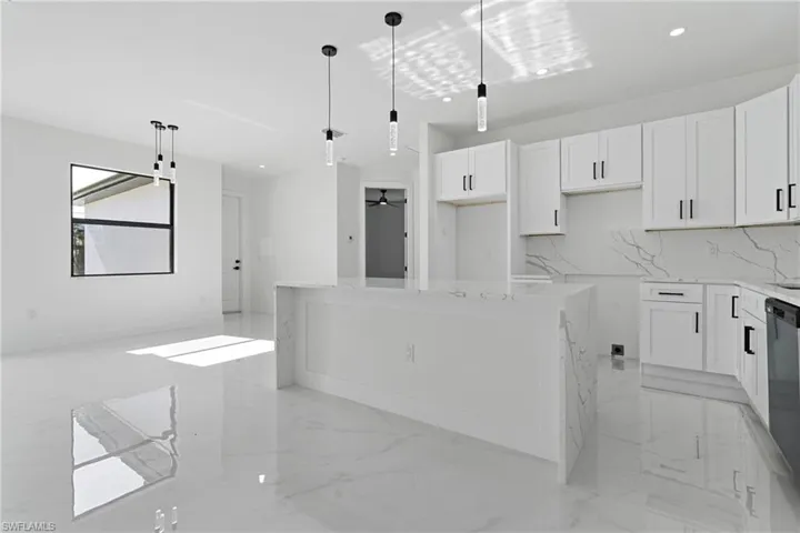 Kitchen with decorative backsplash, marble finish floor, pendant lighting, a kitchen island, and white cabinets