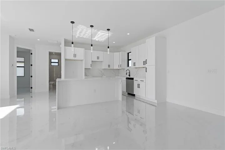 Kitchen featuring stainless steel dishwasher, visible vents, marble finish floor, white cabinets, and a sink