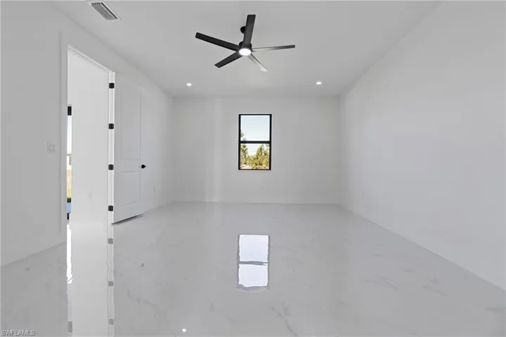 Unfurnished room featuring ceiling fan, marble finish floor, and visible vents