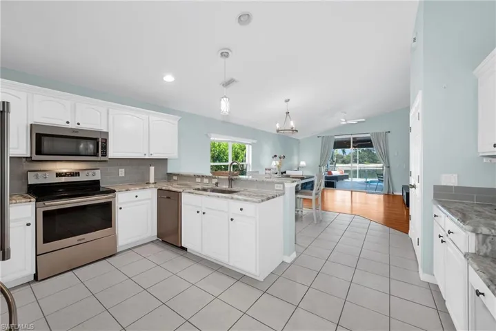 Kitchen featuring white cabinetry, stainless steel appliances, granite countertops, and a tiled backsplash