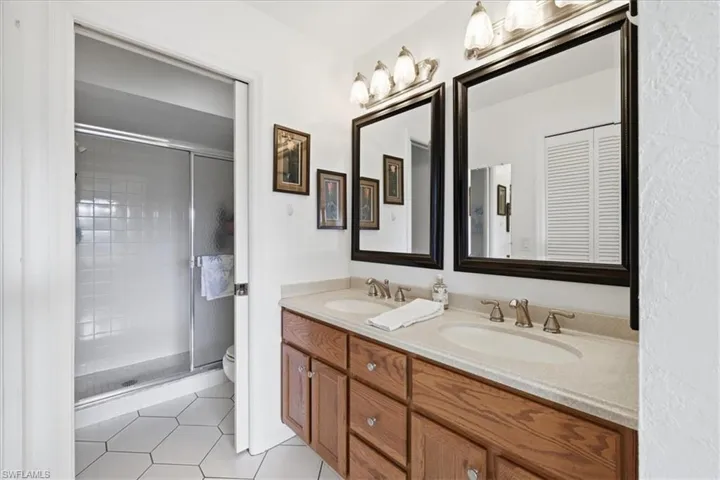 Full bathroom with double vanity, a shower stall, and light tile patterned flooring