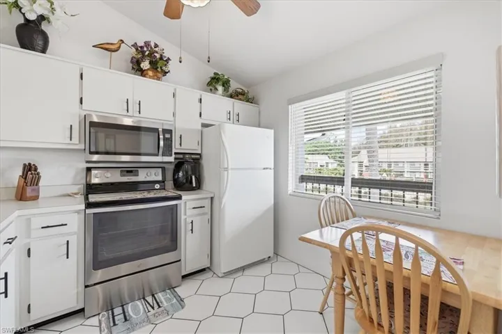 Kitchen featuring stainless steel appliances, light countertops, a ceiling fan, lofted ceiling, and white cabinetry