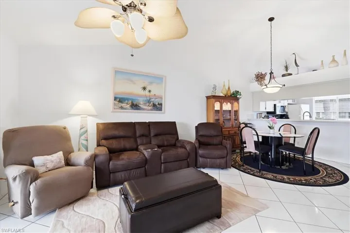 Living room featuring light tile patterned floors, a ceiling fan, and lofted ceiling