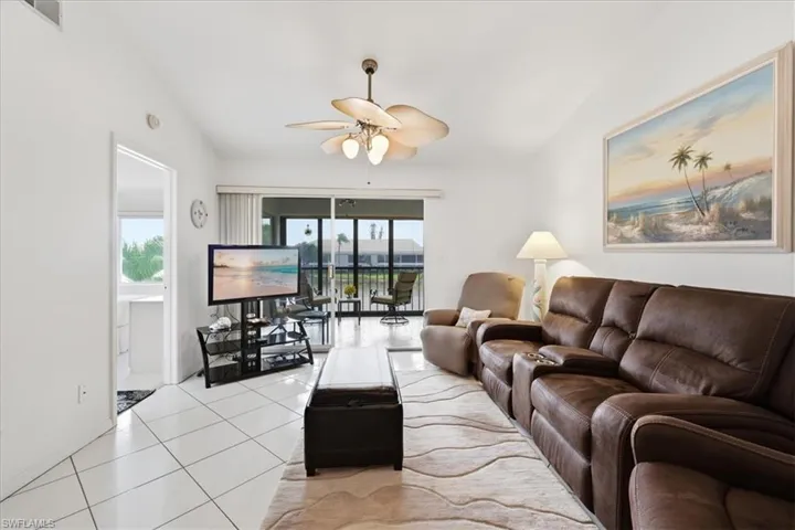 Living area with ceiling fan, tile patterned flooring, and lofted ceiling