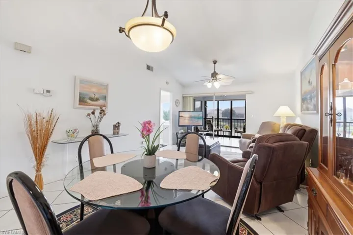 Dining area with vaulted ceiling, light tile patterned floors, and ceiling fan