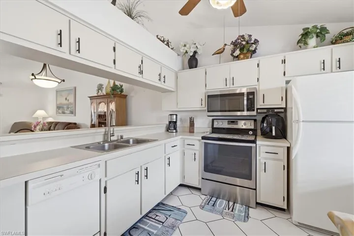 Kitchen with stainless steel appliances, light countertops, white cabinets, a ceiling fan, and open floor plan