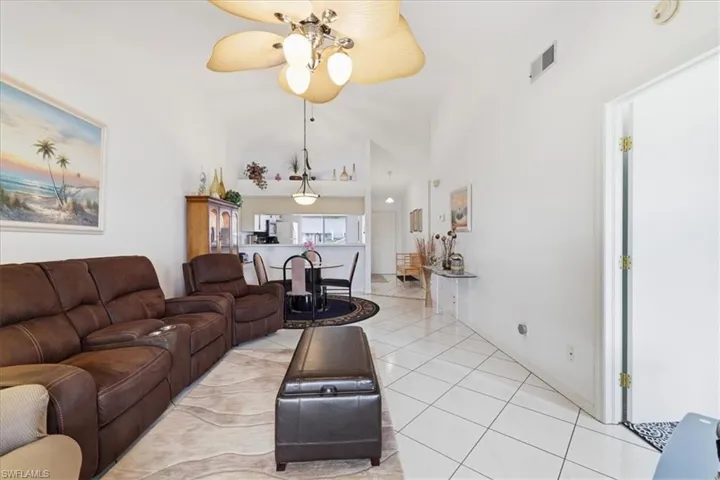 Living room featuring lofted ceiling, light tile patterned flooring, and ceiling fan