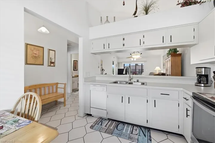 Kitchen with light countertops, white cabinets, white dishwasher, a high ceiling, and stainless steel stove