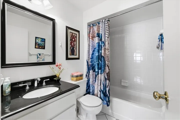 Full bathroom with vanity, shower / bath combo with shower curtain, and tile patterned floors