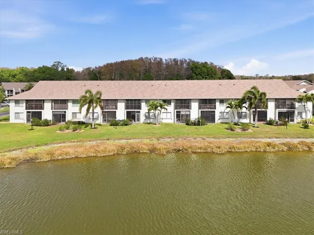 Back of house with a water view and a lawn