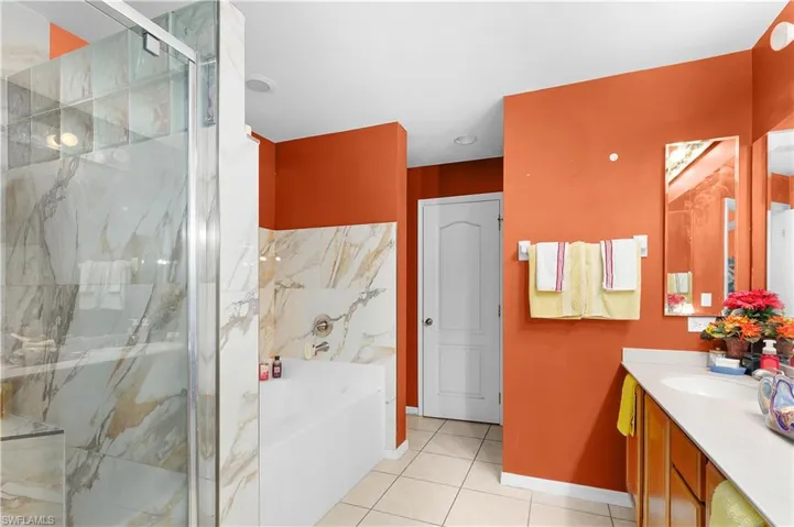 Full bath with vanity, a marble finish shower, a bath, and tile patterned floors