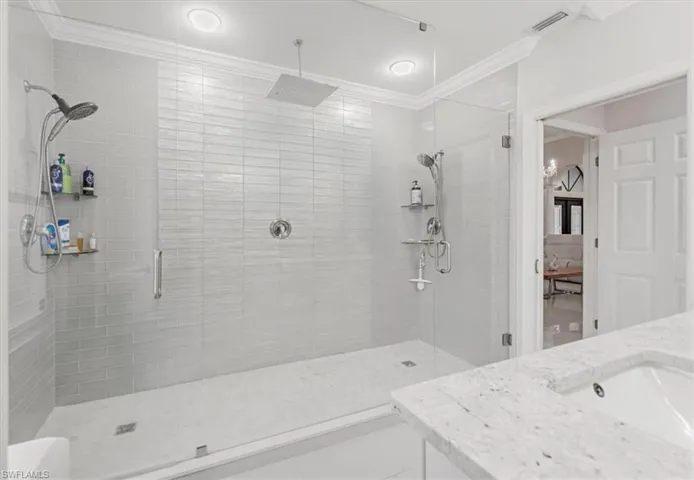 Bathroom with a shower stall, vanity, tile patterned flooring, and crown molding
