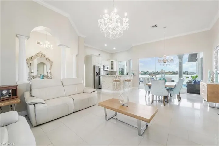 Living room featuring a chandelier, ornamental molding, light tile patterned floors, arched walkways, and recessed lighting