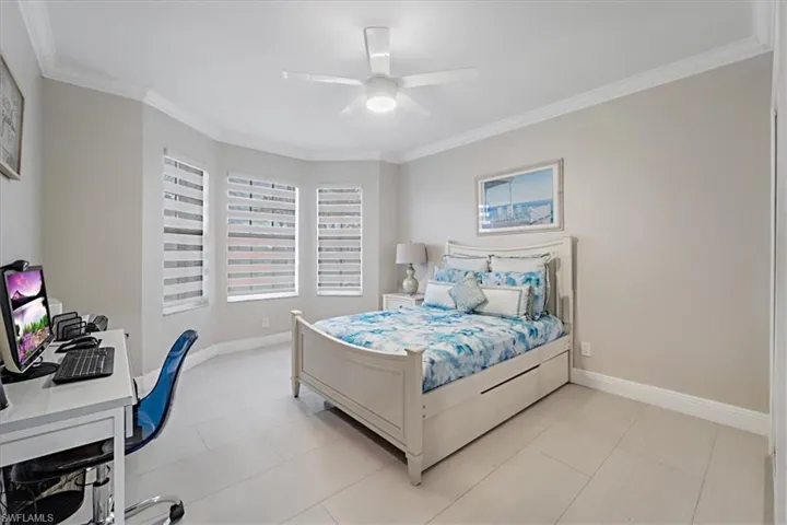 Bedroom featuring a desk, crown molding, a ceiling fan, and light tile patterned floors