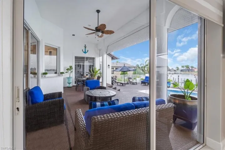 View of patio with a ceiling fan, an outdoor living space with a fire pit, and a water view