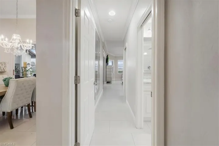 Hall featuring crown molding, light tile patterned flooring, and a chandelier