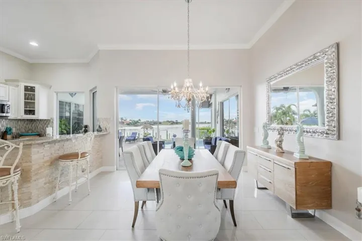 Dining room featuring crown molding, light tile patterned flooring, and a chandelier