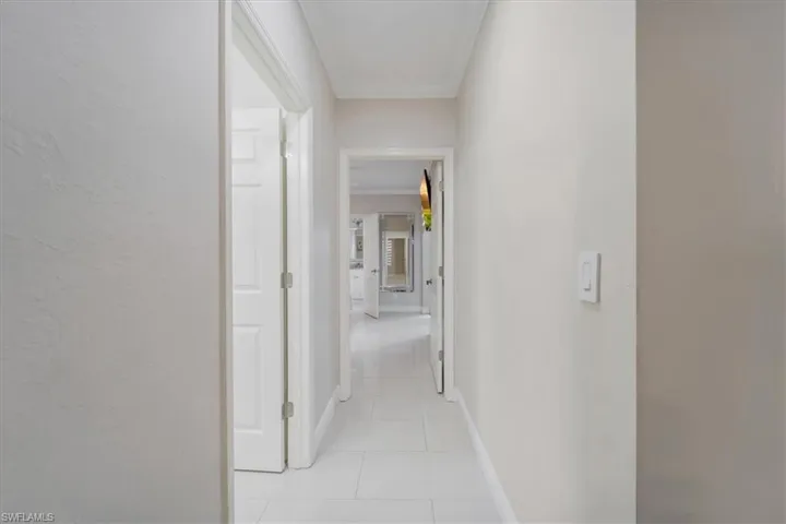 Hall with crown molding and light tile patterned floors