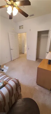 Bedroom with light carpet, ceiling fan, and a closet