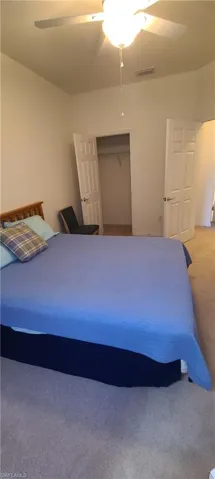 Carpeted bedroom featuring a ceiling fan and a closet