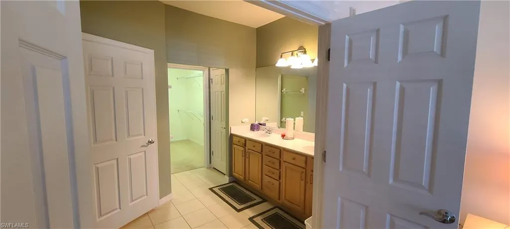Full bathroom with light tile patterned floors, double vanity, and a closet