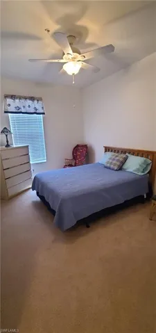 Carpeted bedroom with a ceiling fan