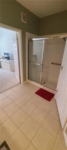Full bath with light tile patterned flooring and a stall shower
