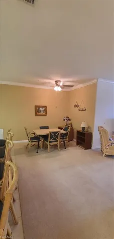Dining area featuring ornamental molding, light colored carpet, and ceiling fan