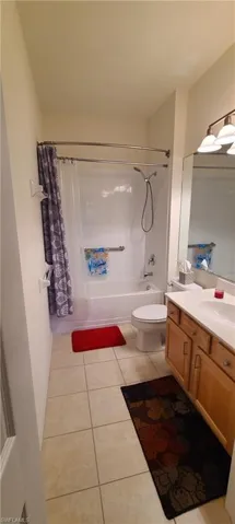 Full bathroom with shower / bath combination with curtain, vanity, and light tile patterned flooring