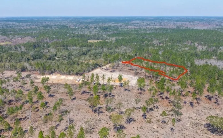 Aerial overview of property's location featuring property boundaries highlighted and a heavily wooded area