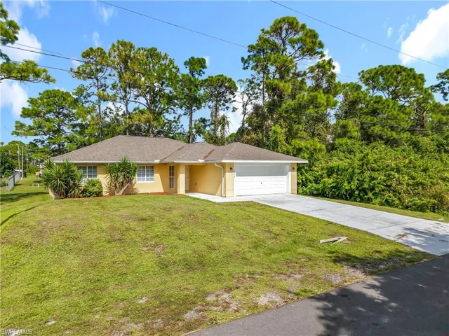 Ranch-style house with concrete driveway, a garage, a front lawn, and stucco siding