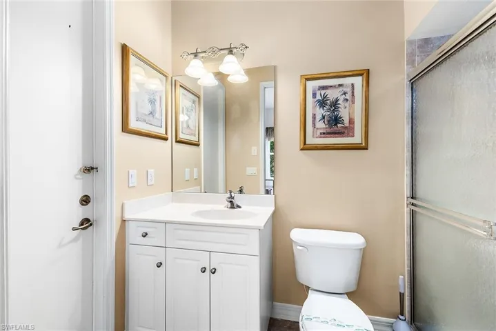 Bathroom featuring a shower with door, vanity, and toilet