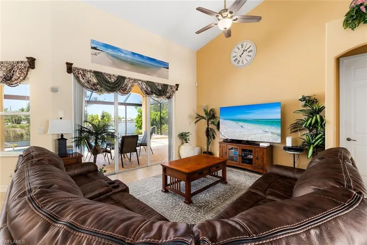 Living room with high vaulted ceiling, tile flooring, and ceiling fan