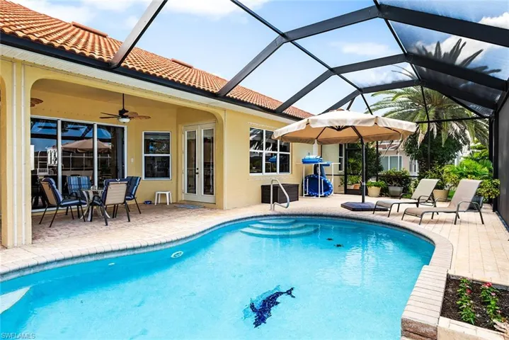 View of pool featuring a patio area, glass enclosure, and ceiling fan