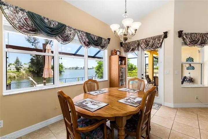 Tiled dining area featuring an inviting chandelier, french doors, and a water view