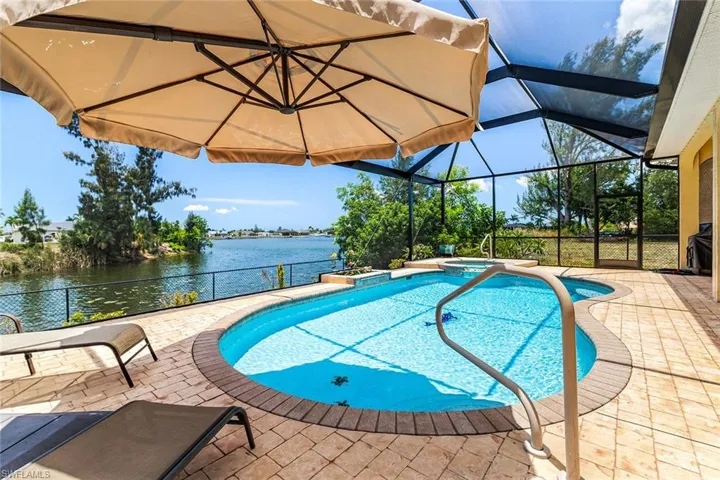 View of swimming pool featuring a patio, glass enclosure, and a water view