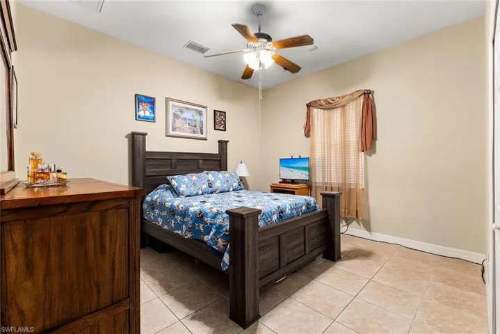 Tiled bedroom featuring ceiling fan