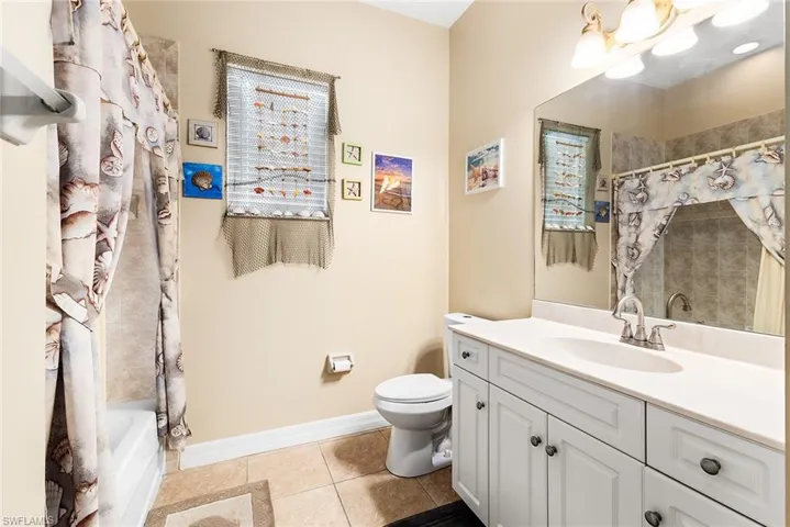 Full bathroom featuring vanity with extensive cabinet space, tile flooring, toilet, and shower / bath combo