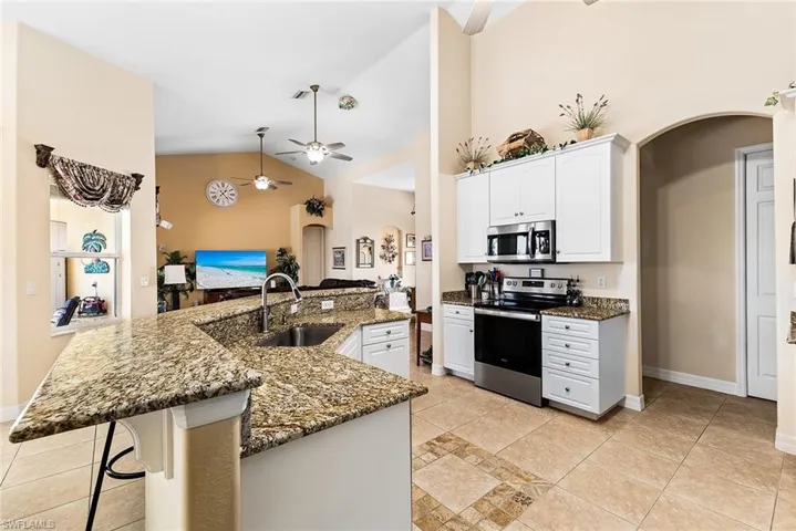 Kitchen with white cabinetry, stainless steel appliances, sink, light tile flooring, and ceiling fan