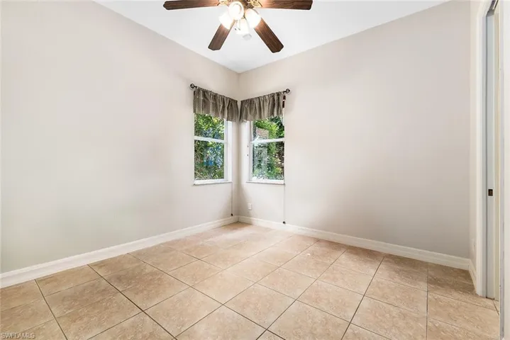 Empty room with ceiling fan and light tile floors