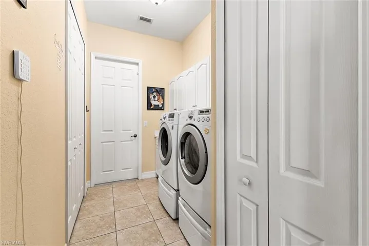 Laundry area with cabinets, light tile flooring, and washing machine and clothes dryer