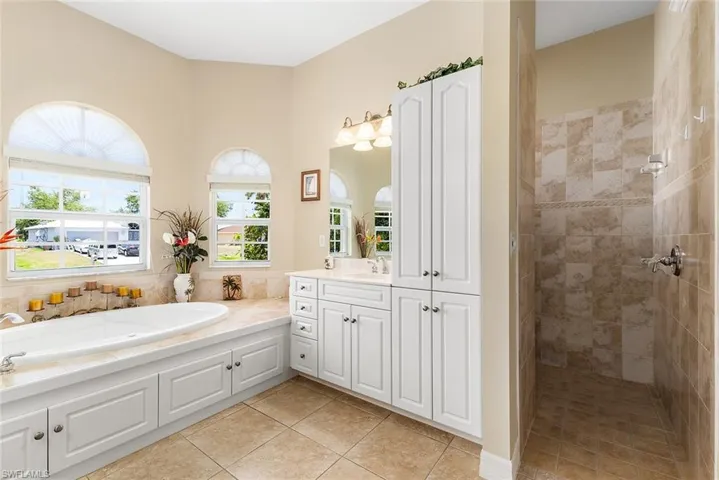 Bathroom featuring tile flooring, vanity, and plus walk in shower