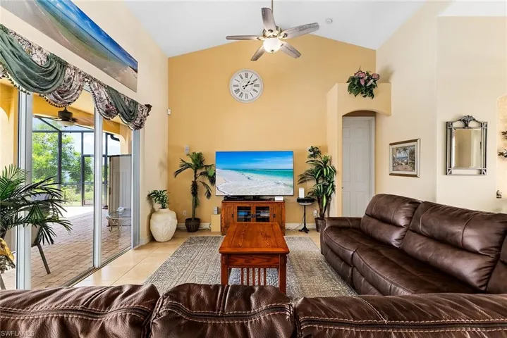 Living room featuring tile floors, high vaulted ceiling, and ceiling fan