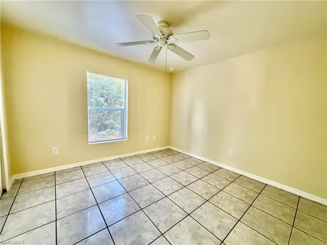 Empty room featuring light tile patterned floors and a ceiling fan