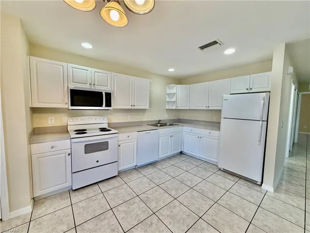 Kitchen with white appliances, white cabinets, open shelves, light countertops, and light tile patterned floors
