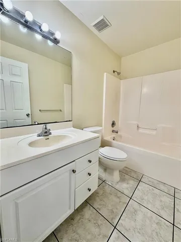 Bathroom with vanity, tub / shower combination, and light tile patterned floors