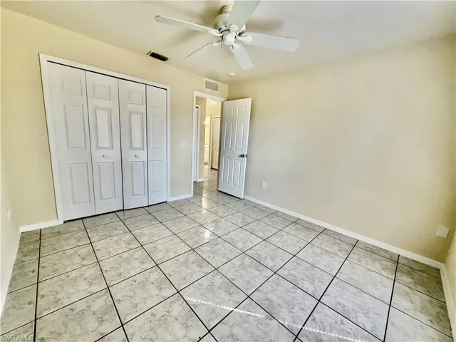 Unfurnished bedroom featuring a ceiling fan, a closet, and light tile patterned floors