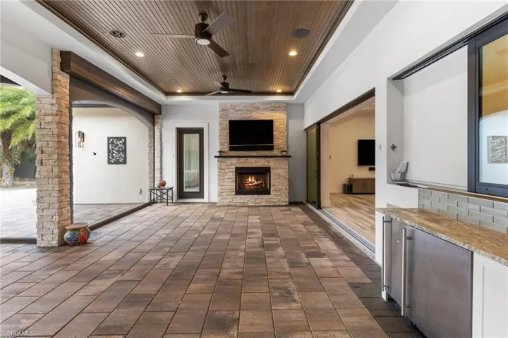 Screened patio with summer kitchen, ice maker, fridge, and gas fireplace